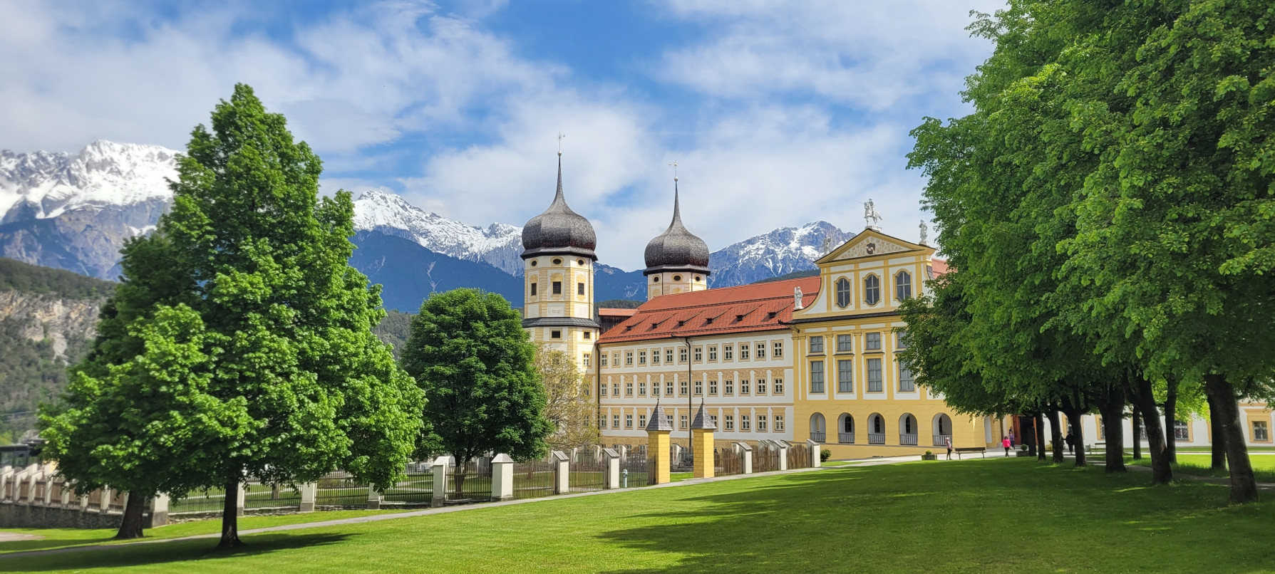 Klosteranlage mit Zwiebelt&uuml;rmen vor Alpenpanorama als Reiseziel f&uuml;r Busreisen